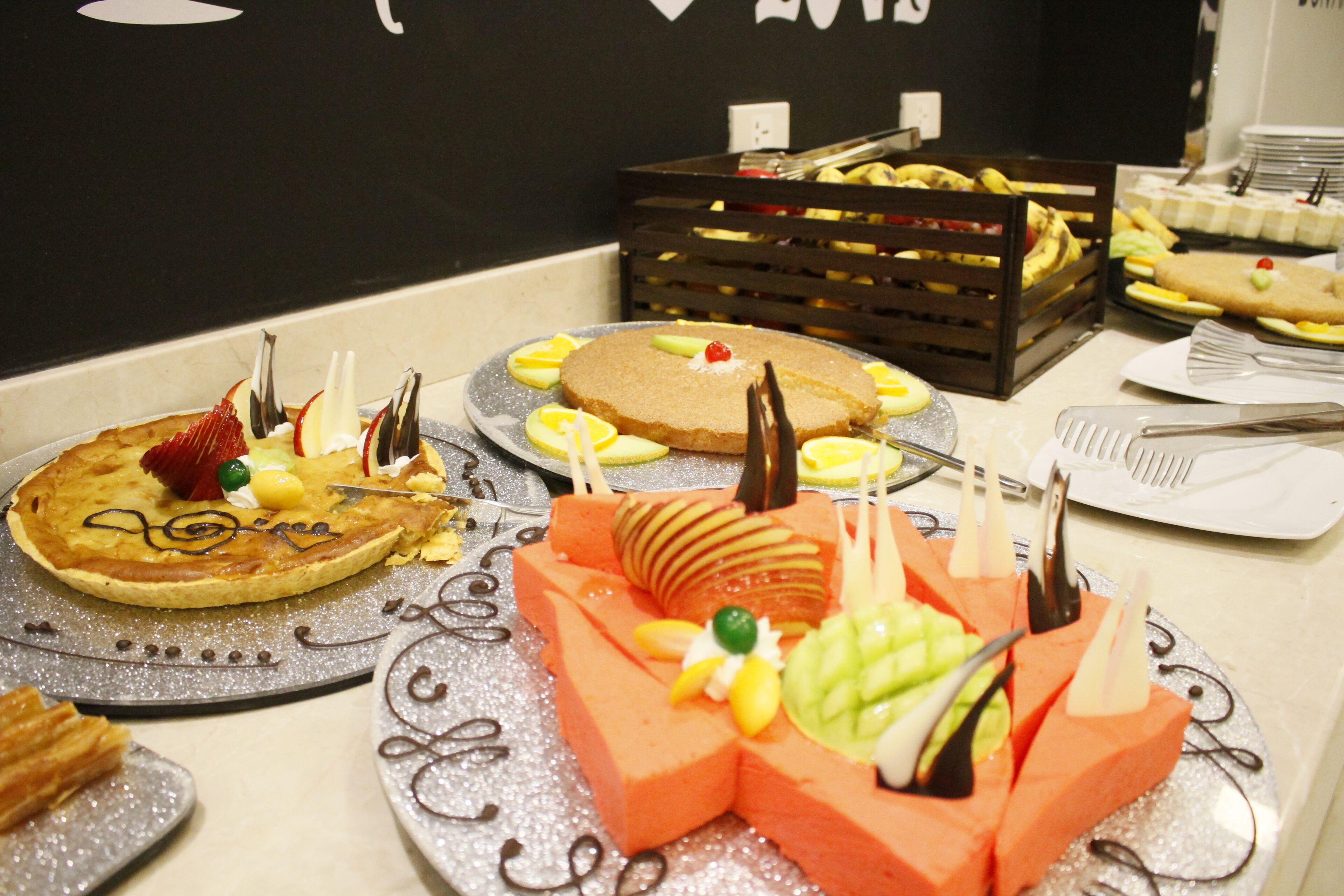Una variedad de postres sobre una mesa, incluyendo pasteles y arreglos de frutas.