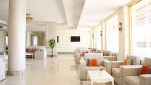 A spacious hotel lobby with a modern design, featuring a large seating area, a flat-screen TV, and large windows allowing natural light. - Gloria Aqua Park Hotel (Aswan)