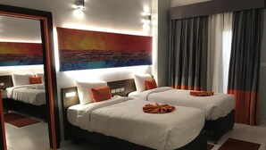 A hotel room with two beds, a large mirror, and a painting of a sunset. - Gloria Aqua Park Hotel (Aswan)