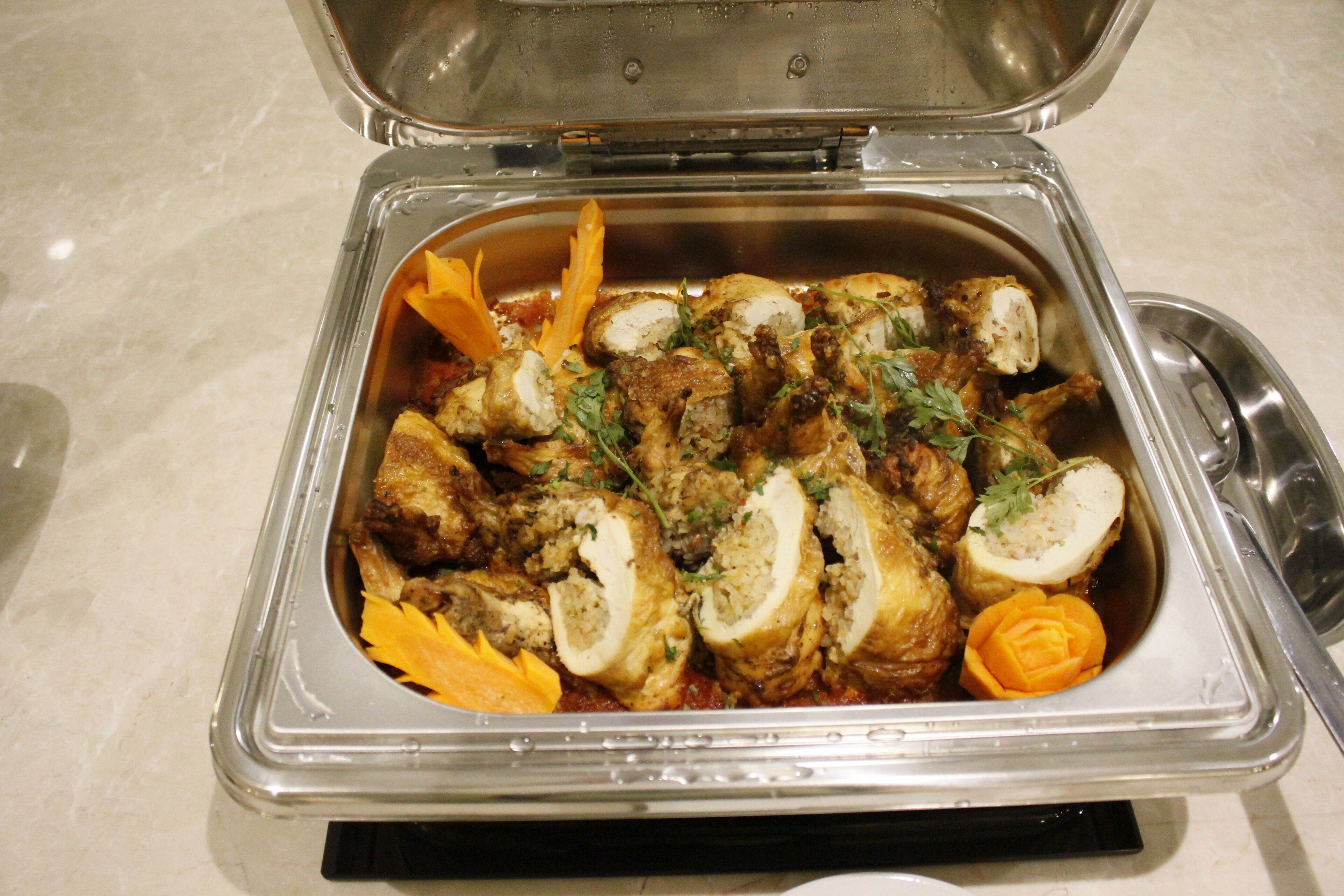 A buffet with various dishes including meat, vegetables, and a decorative orange slice.