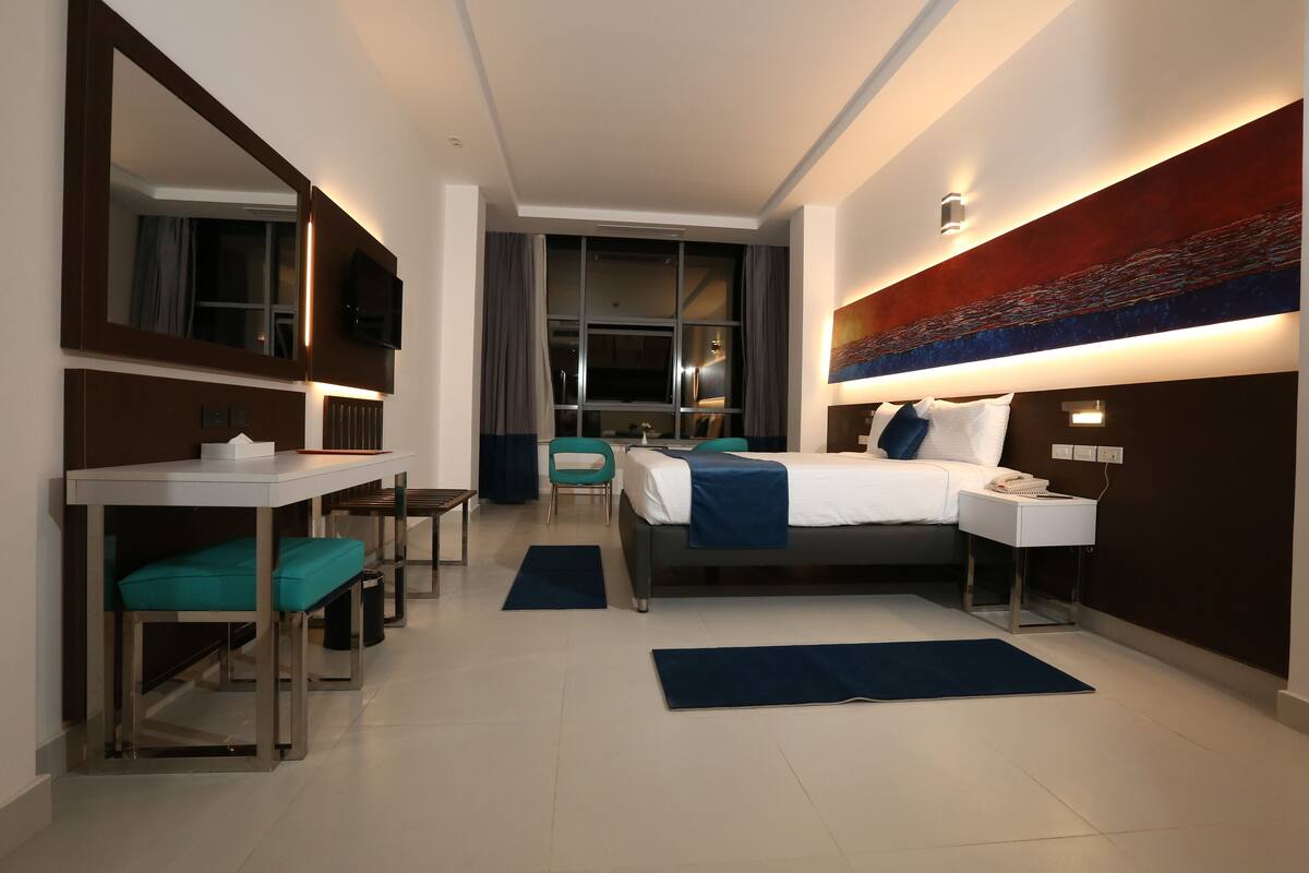 Ein modernes Hotelzimmer mit Bett, Nachttisch, Schreibtisch und Stuhl.