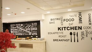 A modern kitchen area with a word cloud wall displaying food-related words. - Gloria Aqua Park Hotel (Aswan)