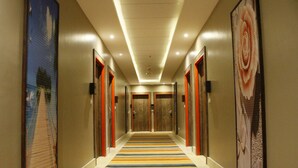 A hotel hallway with a striped carpet, wooden doors, and framed artwork on the walls. - Gloria Aqua Park Hotel (Aswan)