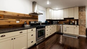 A modern kitchen with wooden paneling, stainless steel appliances, and light-colored cabinetry. - Large, modern 2 bedroom in the heart of Forest Park (Forest Park)