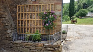 A stone wall with a wooden fence and a flower box containing purple flowers.