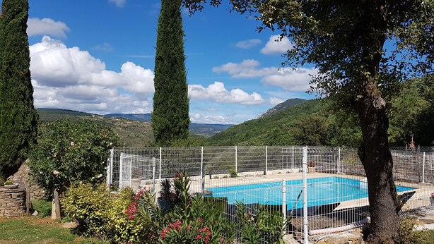 A swimming pool surrounded by a white fence, with a mountainous landscape in the background.