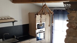A modern kitchen with wooden cabinets, a built-in oven, and a dining area with a table and chairs.