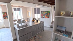 A modern kitchen with a central island, a dining area with chairs, and artwork on the walls. - DIMORE DEL CENTRO - Domus Coeli (Salò)