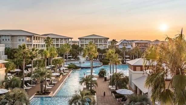 A resort with multiple buildings, a central swimming pool, and palm trees. - Walk to the beach & Lagoon Pool-Bumblebee Cottage (Panama City Beach)
