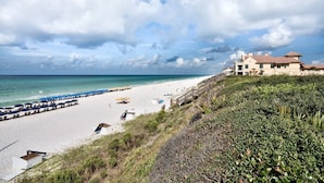 A beach with a large house, a pier, and a clear sky. - Walk to the beach & Lagoon Pool-Bumblebee Cottage (Panama City Beach)