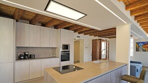 Eine moderne Küche mit Kochinsel, integrierten Geräten und Holzbalken an der Decke.
