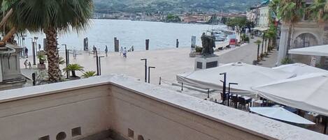 Una terraza con vista al agua, palmeras y una estatua.