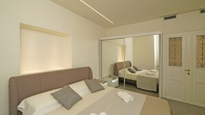 Ein modernes Hotelzimmer mit einem großen Bett, einem Nachttisch, einem Spiegel und einem Kleiderschrank.