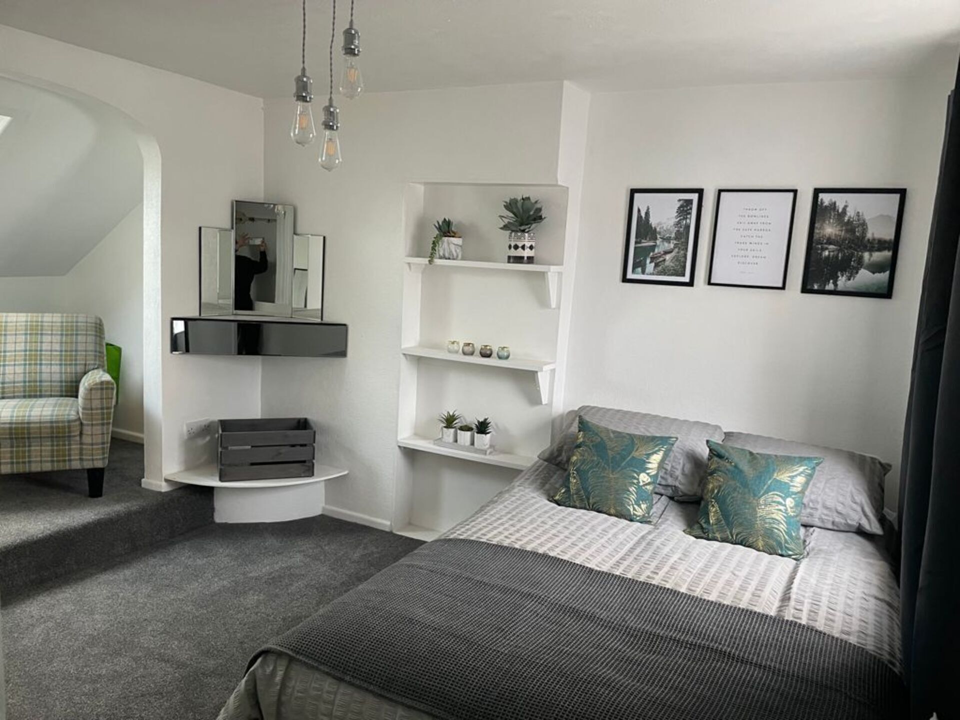 Ein modernes Schlafzimmer mit Bett, Stuhl, Schreibtisch und Regalen mit Dekoration.