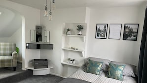 Une chambre moderne comprenant un lit, une chaise, un bureau et des étagères ornées d’objets décoratifs.