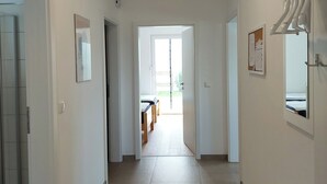 A hallway with white walls, a ceiling light, a door with a mirror, and a window with a view. - Vacation apartment for 2-3 persons on the outskirts of Wittingen (Wittingen)