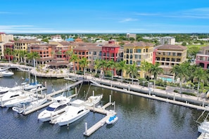 A marina with colorful buildings and boats docked. - Esplanade Condo | Courtyard View, Gym, Pool & Spa (Marco Island)