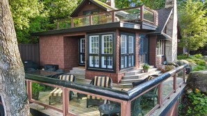 Una casa de dos pisos con balcón y zona de estar al aire libre.