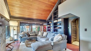 Un salón amplio con un sofá seccional grande, una chimenea y estanterías empotradas con objetos decorativos.
