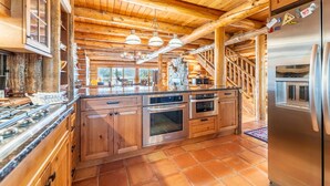 Een ruime keuken met houten kastjes, een groot eiland en roestvrijstalen apparatuur.