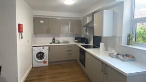A compact kitchen with a washing machine, microwave, and a window with a view. - Inviting 3-bed Apartment in Stockton-on-tees (Stockton-on-Tees)