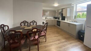 A modern kitchen with wooden flooring, white cabinets, and a dining area with a wooden table and chairs. - Inviting 3-bed Apartment in Stockton-on-tees (Stockton-on-Tees)