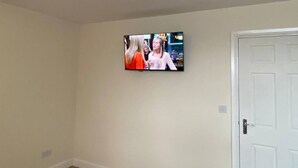Un téléviseur fixé au mur dans une pièce dont la porte est blanche.
