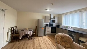 Une cuisine compacte comprenant une table à manger, des chaises, un réfrigérateur, un four à micro-ondes et un lave-linge.
