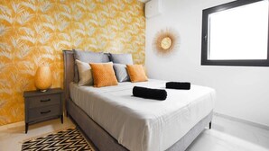 A modern bedroom with a large bed, a nightstand, a decorative wall piece, and a window. - Palm 1BR next to Gazoz Beach by HolyGuest (Tel Aviv-Yafo)
