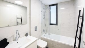 A modern bathroom with a white sink, mirror, and bathtub. - Palm 1BR next to Gazoz Beach by HolyGuest (Tel Aviv-Yafo)