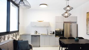 A modern kitchen with white cabinets, a stainless steel refrigerator, and a dining area with a table and chairs. - Palm 1BR next to Gazoz Beach by HolyGuest (Tel Aviv-Yafo)