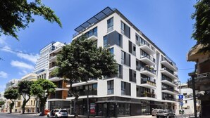 A modern multi-story building with balconies, large windows, and a flat roof. - Palm 1BR next to Gazoz Beach by HolyGuest (Tel Aviv-Yafo)