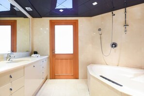 A modern bathroom with a wooden door, a large mirror, a bathtub, and a shower.
