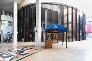 A modern building with a curved glass facade and a blue entrance canopy.