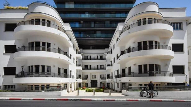 A modern multi-story building with a symmetrical facade, balconies, and a central entrance.