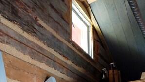 Un intérieur en bois avec un escalier en bois, une fenêtre et une porte.