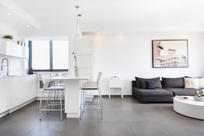 Une cuisine moderne avec des meubles blancs, un coin repas comprenant des chaises, un canapé et une table basse.
