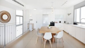 Une cuisine moderne avec des meubles blancs, une table à manger en bois et une grande fenêtre.