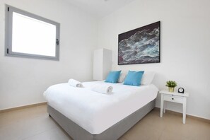Ein Schlafzimmer mit einem Bett, einem Nachttisch, einem Fenster und einem Bild an der Wand.