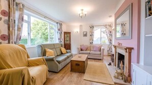 A cozy living room with a sofa, armchair, and a fireplace. - The Spinney, Saxtead near Framlingham (Woodbridge)