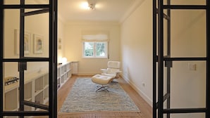 A hallway with a white chair, a window with white valance, and a radiator. - FLH Serralves House with Garden (Oporto)