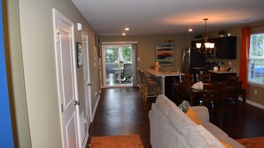 A spacious living area with a sofa, dining table, and chairs. There is a kitchen area with a refrigerator and a dining table. A sliding glass door leads to an outdoor patio. - Comfortable, Beautiful Townhome in quaint neighborhood w/ patio deck (Henrico)