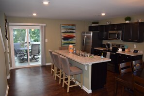 A modern kitchen with dark cabinets, a stainless steel refrigerator, and a built-in microwave.
