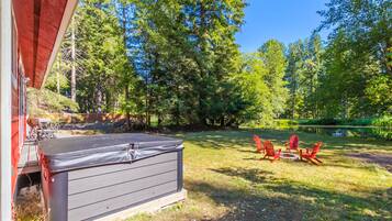 A backyard with a hot tub, outdoor furniture, and a pond.