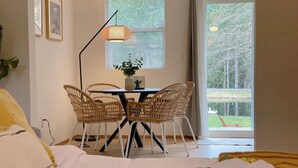 Hotellihuone, jossa on sänky, ruokapöytä tuoleineen, lamppu ja ikkunasta avautuva näkymä järvelle.