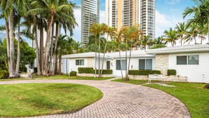 A modern building with a brick pathway, surrounded by palm trees and a well-maintained lawn. - 2 Bedroom 2 Bath Beach 1 min Walk 8 People Keyless Free Parking Flex Check in (Sunny Isles Beach)