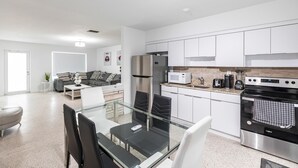 A modern kitchen with white cabinets, stainless steel appliances, and a glass dining table. - 2 Bedroom 2 Bath Beach 1 min Walk 8 People Keyless Free Parking Flex Check in (Sunny Isles Beach)