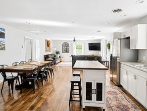 A modern kitchen with a central island, white cabinetry, and a dining area with a wooden table and chairs. -  10 Min Liberty University|Family Friendly w/King&Patio/Grill|Playset (FOREST)