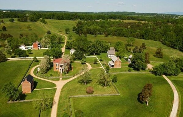 An aerial view of a rural property with multiple buildings, green fields, and a winding road.