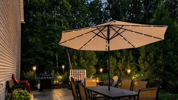 An outdoor patio with a table and chairs, a grill, and string lights. - Modern Family Haven 10 Min to Liberty/ King Bed•Patio•Grill•Firepit•Playset (FOREST)